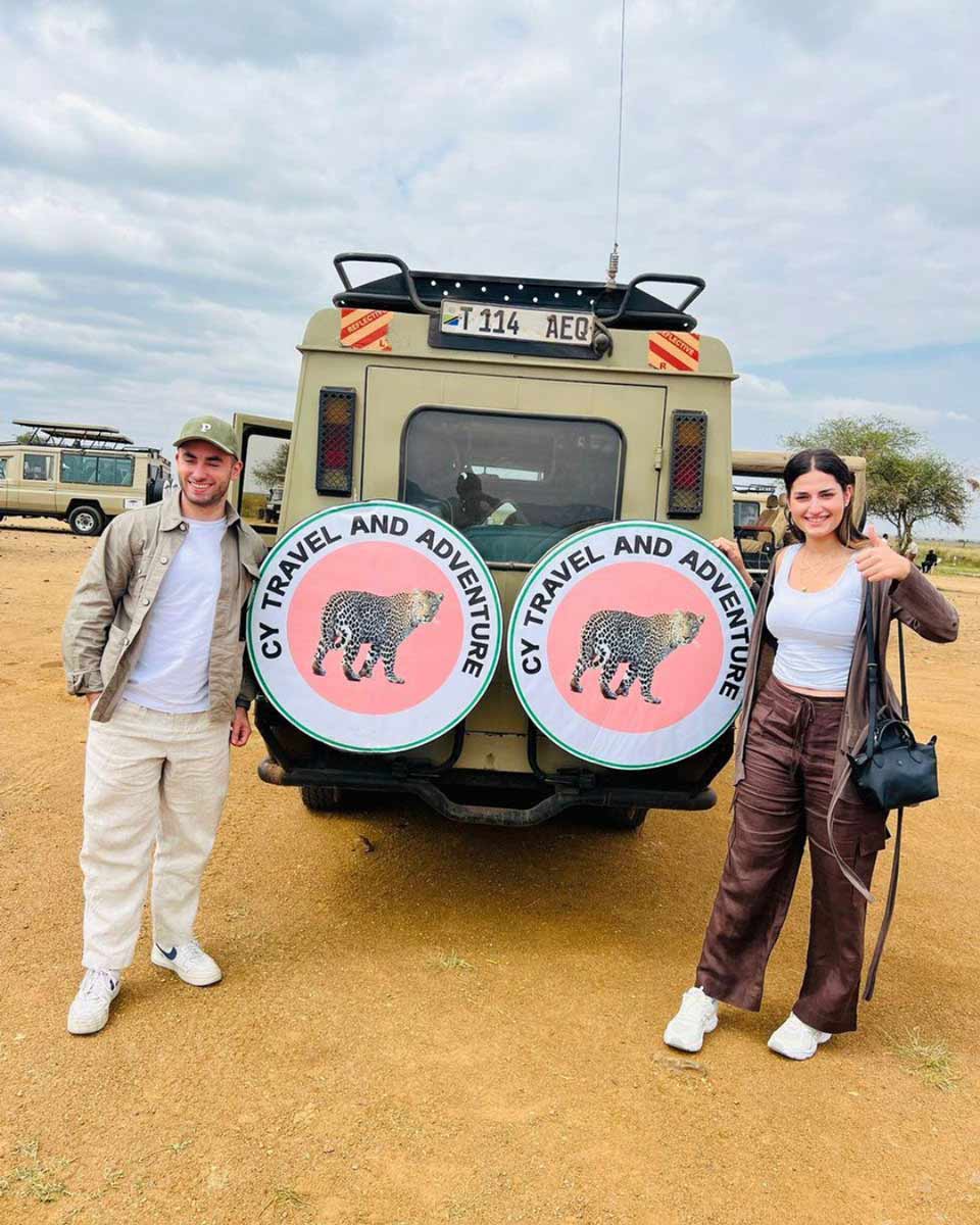 A white couple posing next to a safari jeep