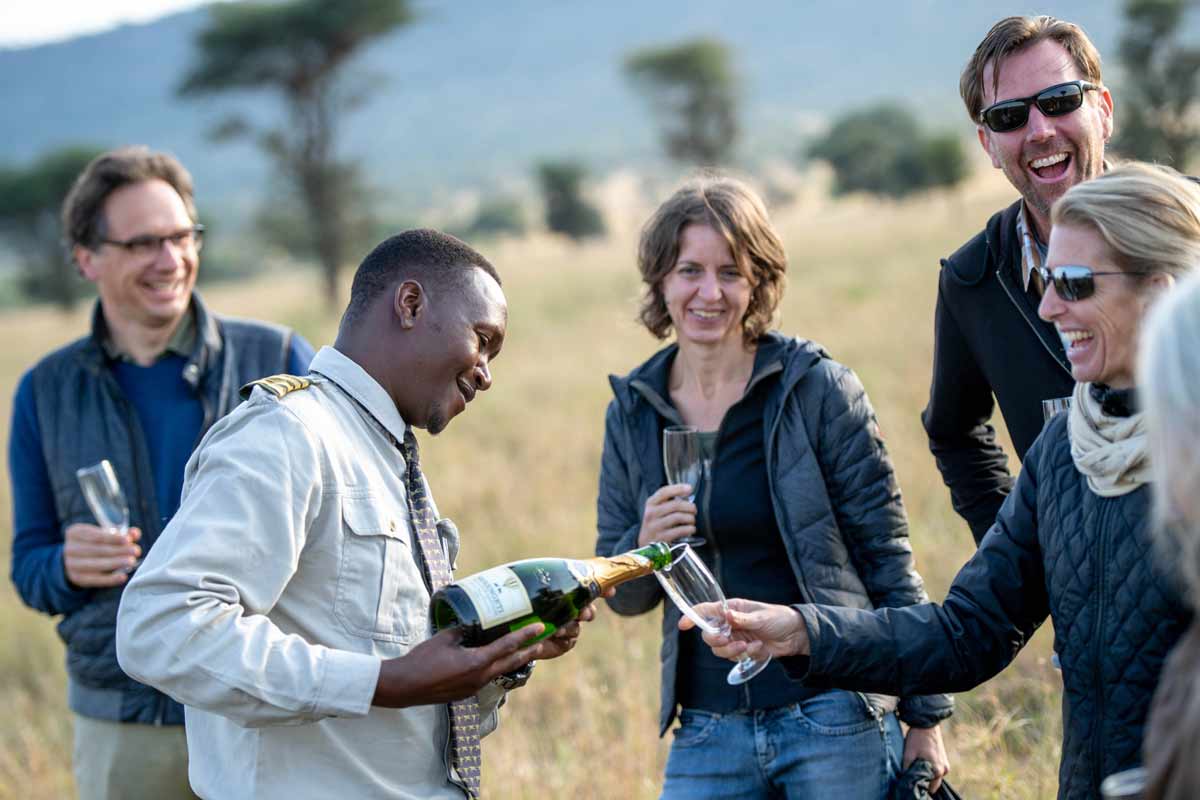 A group of tourists drinking champagne in the national park, smiling and laughing.