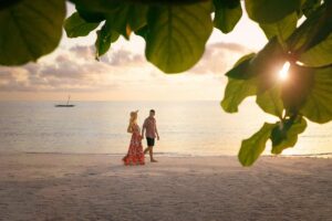 A couple walking on the beach, at sunset.