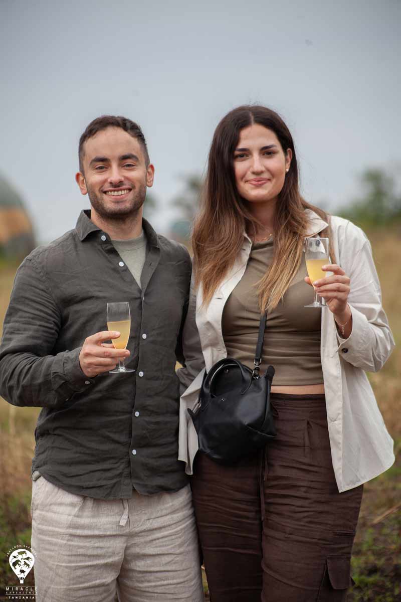 A white couple smiling at the camera, holding glasses of champagne in their hands